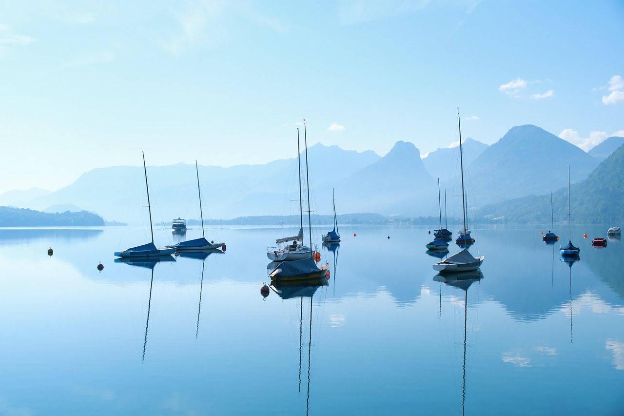 Calm blue lake with boats and soft morning light, space for reflection and peace
