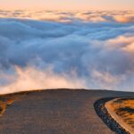 A winding road leading towards clouds and an open horizon far from a need to control