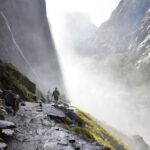 Three people walking along a mountain trail disappearing into mist, symbolising uncertainty and continuing forward without knowing what lies ahead.